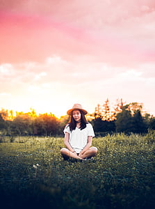 woman sitting on green grass during daytime thumbnail