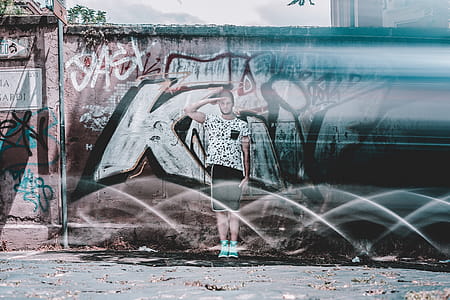 Man in White Shirt and Black Shorts Saluting Graffiti at Daytime thumbnail