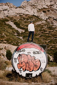 person wearing white sweater standing in front of the rocky mountain thumbnail