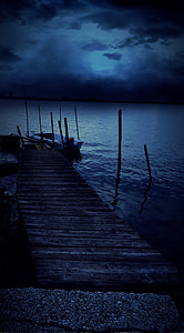brown wooden dock with white motor boat on water at night time thumbnail
