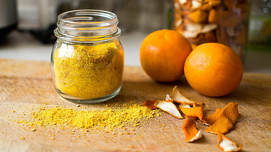 brown powder in glass jar beside two orange fruits thumbnail