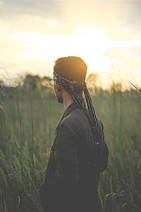 selective focus photography of man wearing bandanna and black jacket near grass field thumbnail