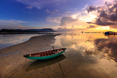 green and brown boat on seashore during golden hour thumbnail