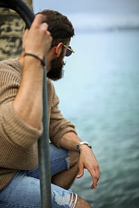 man holding a handrail while watching the ocean thumbnail