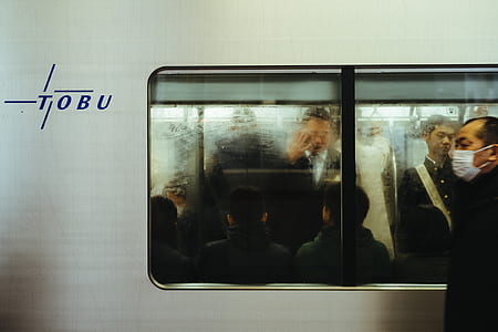man wearing black jacket with white mouth mask walking near train thumbnail
