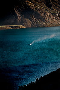 person riding boat near trees and cliff during daytime thumbnail