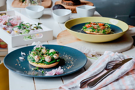 vegetable salad topped bread on round blue ceramic plate on top of white table thumbnail