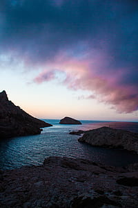 cliff near body of water at cloudy sky during daytime thumbnail