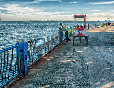 person standing on rails beside body of water during daytime thumbnail