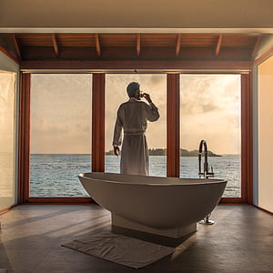 man standing near glass window beside white bathtub thumbnail
