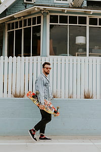 man holding skateboard on road thumbnail