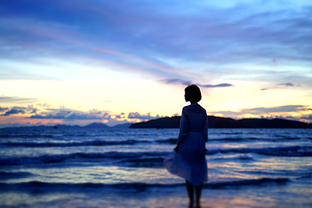 woman standing near the shore during sunrise thumbnail