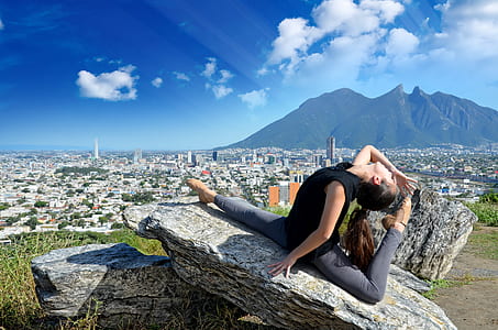 woman in black crew-neck t-shirt and grey pants doing acrobatic post on rock thumbnail
