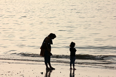 silhouette of man and girl standing on seashore thumbnail