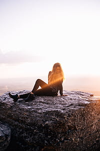 woman wearing black leggings sitting on rock during day thumbnail