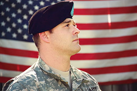 Man Wearing Combat Hat And Top Looking Up Near Flag Of America thumbnail