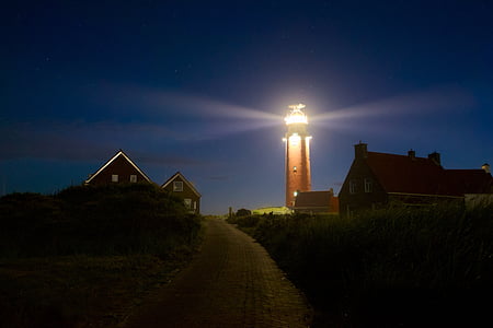 brown lighted lighthouse between houses thumbnail
