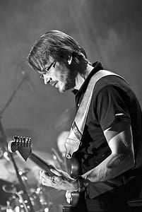 grayscale photography of man playing guitar thumbnail
