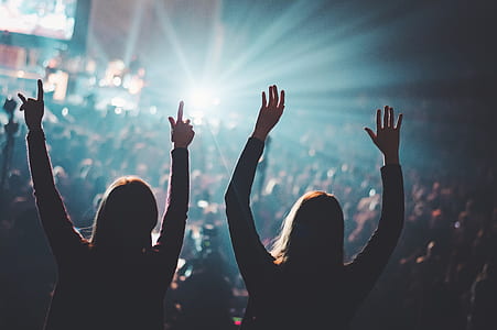 focus photography of two women raising both hands front of concert thumbnail