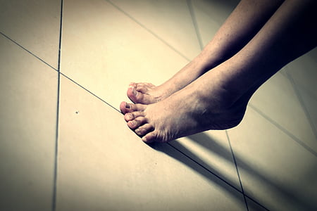 person's feet on white ceramic tiles thumbnail