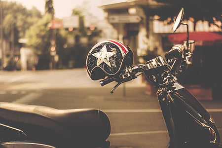 black and gray motor scooter with helmet parked thumbnail