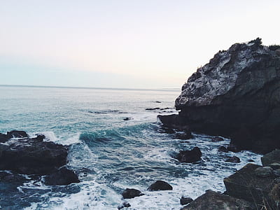 ocean waves hugging black rocky shore thumbnail