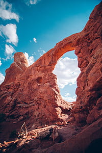 low angle photography of arch cliff under blue sky thumbnail