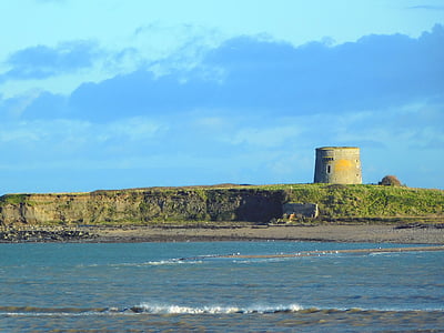 gray concrete tower by cliff near shore at daytime thumbnail
