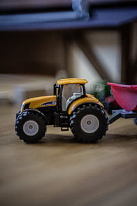 shallow focus photo of yellow tractor toy on brown wooden table thumbnail