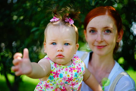 selective focus photo of woman carrying baby in floral sleeveless top thumbnail