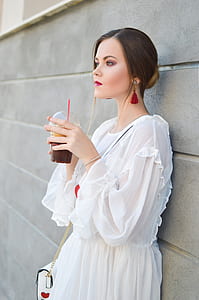 woman leaning on concrete wall while holding smoothies thumbnail