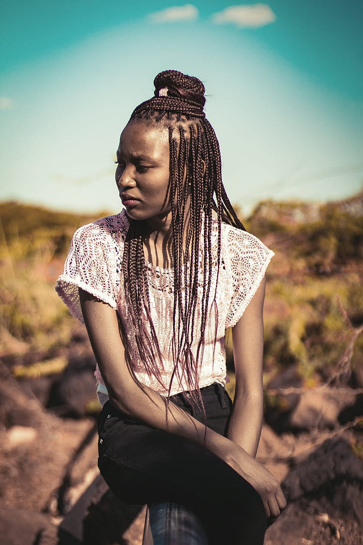 woman sitting on rock wearing white crochet blouse
