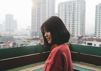 woman in red sweater on green rooftop near white buildings during daytime thumbnail