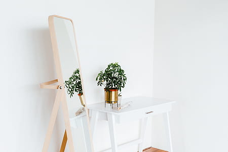 white wooden table beside rectangular mirror with beige wooden frame thumbnail