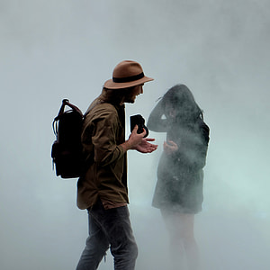 man standing while holding black camera in front of woman in black dress thumbnail