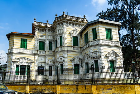 Yellow and White Painted Mansion Near Black Iron Gate thumbnail
