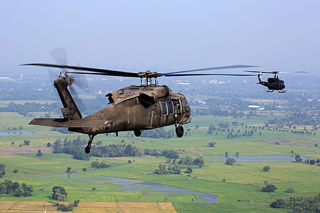 Brown Helicopter Flying Above Green Field during Daytime thumbnail