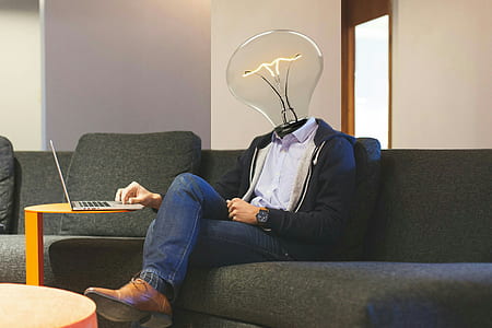 bulb-headed man sitting on sofa using laptop thumbnail