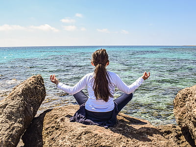 photo of girl sitting on gray rock near body of water thumbnail