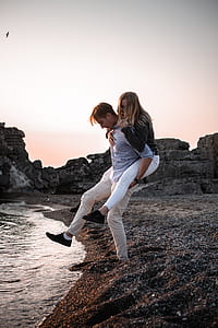 man carrying woman near sea thumbnail