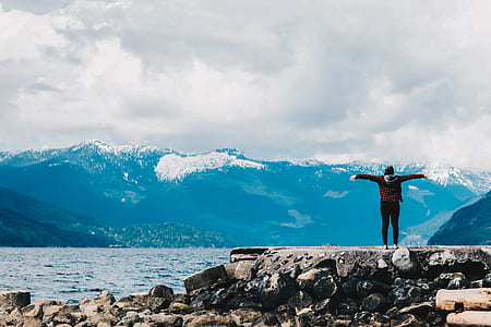 person in red jacket stretching arm standing on plateau thumbnail