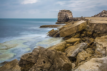 brown rock formation near calm sea water at daytime thumbnail