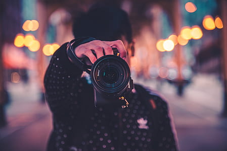 man in black jacket holding black DSLR camera thumbnail