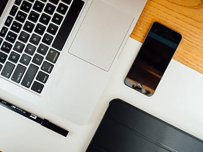 space gray iPhone 5s near MacBook Pro on brown wooden surface thumbnail