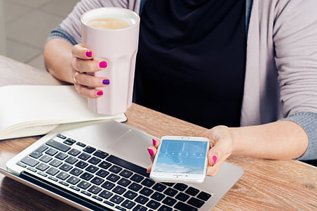 person using phone in front of laptop computer thumbnail
