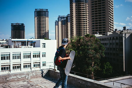 A young caucasian skateboarder carrying backpack on a rooftop thumbnail
