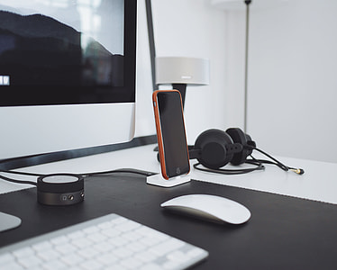space gray iPhone 6 with brown case on stand beside iMac thumbnail