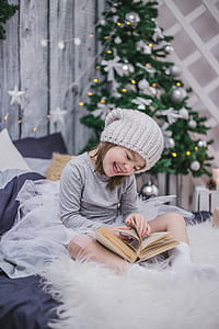 girl in gray sweatshirt and kit cap sitting on bed thumbnail