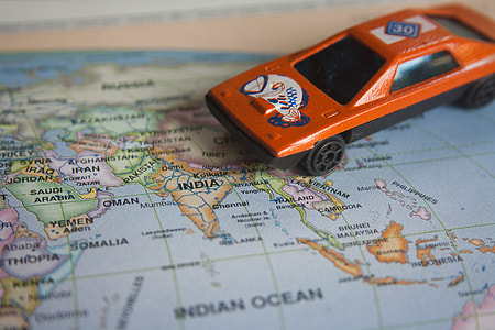 close-up photography of orange car toy on blue world map thumbnail