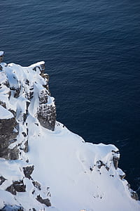 photo of mountain filled with snow beside body of water thumbnail